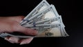 Close-up of female hands holding a pack of one hundred dollar bills.The concept of paying for goods and services, getting paid,