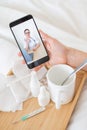 Close-up of female hands holding a phone with a doctor on the screen. Remote appointment with a doctor. A woman on sick Royalty Free Stock Photo