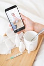 Close-up of female hands holding a phone with a doctor on the screen. Remote appointment with a doctor. A woman on sick Royalty Free Stock Photo