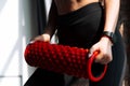 Close-up of female hands holding a red massage cylinder for training. Pilates equipment