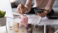 Closeup female hands holding smartphone put euro coin into piggybank Royalty Free Stock Photo