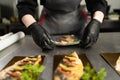 close-up of female hands in the kitchen in a restaurant pack the baked mackerel in plastic wrap.