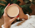 Close-up of female hands with a mug of beverage. Girl in warm sweater is holding hot cup of coffee or cocoa in hands. Top view. Royalty Free Stock Photo