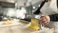 Close up female hands preparing fettucine pasta using traditional machine