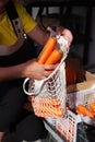 Close-up of female hands put raw carrots in an eco bag. Eco goods replacement of a plastic bag. Fresh vegetable on the