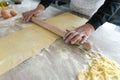 Close up female hands roll the dough preparing homemade pasta