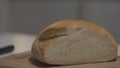 Close up of female hands slicing white bread in slow motion on a wooden board. Action. Cutting freshly baked round Royalty Free Stock Photo