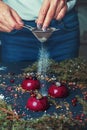 Close up female hands sprinkle powder sugar on Trendy mousse cake with berry glaze decorated with fir tree Meringues Cranberry. Royalty Free Stock Photo