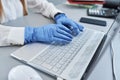 Close up of female hands in surgical gloves on laptop keyboard Royalty Free Stock Photo