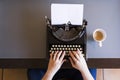 Close up of female hands typing on retro typewriter. Cup of coffee is at right side.Indoors. Top view. Royalty Free Stock Photo