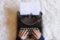 Close up of female hands typing on retro typewriter. Cup of coffee is at right side. Top view. white background. Indoors. Royalty Free Stock Photo