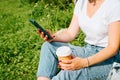 Close-up of female hands using mobile phone and holding disposable cup of coffee outdoors. Royalty Free Stock Photo