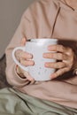 Close-up of female hands in warm pink sweater holding white mug with tea or coffee Royalty Free Stock Photo