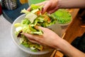 Close up of female hands and woman preparing green salad, cooking in kitchen. Housewife slicing and prepared fresh salad.