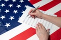 Close-up of female hands writing musical notes on a sheet of sheet music, against the background of the American flag Royalty Free Stock Photo