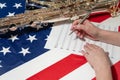 Close-up of female hands writing musical notes on a sheet of sheet music, against the background of the American flag Royalty Free Stock Photo