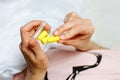 Close up of female hands and yellow foam earplugs. Woman taking the antinoise earplug. White background. Free space for Royalty Free Stock Photo