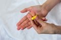 Close up of female hands and yellow foam earplugs. Woman taking the antinoise earplug. White background.