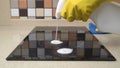 Female hands in protective gloves cleaning the surface of an induction cooker.