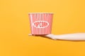Close up female hold in hand classic clear empty striped xl bucket for popcorn isolated on trending yellow orange Royalty Free Stock Photo