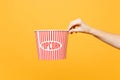 Close up female hold in hand classic clear empty striped xl bucket for popcorn isolated on trending yellow orange Royalty Free Stock Photo