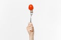 Close up female holds in hand red fresh tomato on fork isolated on white background. Proper nutrition, vegetarian food Royalty Free Stock Photo