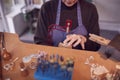 Close Up Of Female Jeweller Working On Piece With Saw In Studio