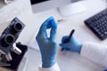 Close Up Of Female Lab Worker Wearing PPE Researching BA.2 Variant Of Covid-19 With Microscope