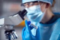 Close Up Of Female Lab Worker Wearing PPE Researching Vaccine With Microscope Royalty Free Stock Photo