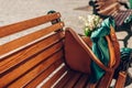 Close up of female leather handbag with tied scarf on bench. Brown purse with bouquet of white spring flowers. Space Royalty Free Stock Photo