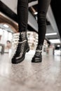 Close-up of female legs in black trendy jeans in leather black stylish lace-up boots. Fashionable woman poses on the shop mall. Royalty Free Stock Photo