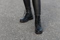 Close up of female legs in black trendy leggings in leather stylish boots. Fashionable woman walks on the pavement. Retro style. Royalty Free Stock Photo