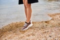 Girl dressed in a black coat in sneakers on the beach Royalty Free Stock Photo