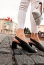 Close-up of female legs in white denim pants in fashionable black leather summer shoes with a stylish bag on the street Royalty Free Stock Photo