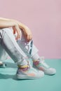 Close up female legs in white jeans and retro style high-top multicolor sport sneakers shoes sitting on the skateboard Royalty Free Stock Photo