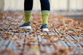 Close-up of a female legs on wooden walking trails covered with autumn leaves