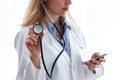 Female medical doctor holding stethoscope and using her smartphone over white background Royalty Free Stock Photo