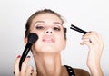 Close-up Female model applying makeup on her face. Beautiful young woman applying foundation on her face with a make up Royalty Free Stock Photo