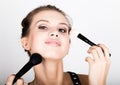 Close-up Female model applying makeup on her face. Beautiful young woman applying foundation on her face with a make up Royalty Free Stock Photo