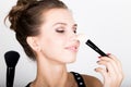 Close-up Female model applying makeup on her face. Beautiful young woman applying foundation on her face with a make up Royalty Free Stock Photo