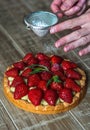 Close up of female pastry chef`s hand decorating  top of delicious French strawberry cake Royalty Free Stock Photo