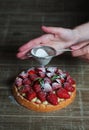 Close up of female pastry chef`s hand decorating  top of delicious French strawberry cake Royalty Free Stock Photo