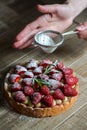 Close up of female pastry chef`s hand decorating  top of delicious French strawberry cake Royalty Free Stock Photo