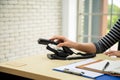 Close up female person hand holding using old telephone calling on desk in office