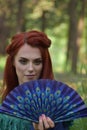 Outdoors female portrait with peacock feather fan in her hand Royalty Free Stock Photo