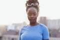 Close-up of female portrait of young beautiful African. Charming black girl with sunglasses and blue T-shirt stands against Royalty Free Stock Photo