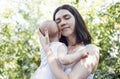 Close up of female portrait of young charming mother holds her cute baby in arms in garden Royalty Free Stock Photo