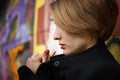 Close-up female portrait of young smiling girl with short blonde hair near the wall with graffiti. Youth culture, street Royalty Free Stock Photo