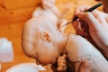 Close-up of female puppeteer decorating reborn, realistic doll of newborn caucasian baby, Royalty Free Stock Photo