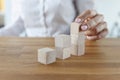 Female putting wooden brick on top of stack, building tower